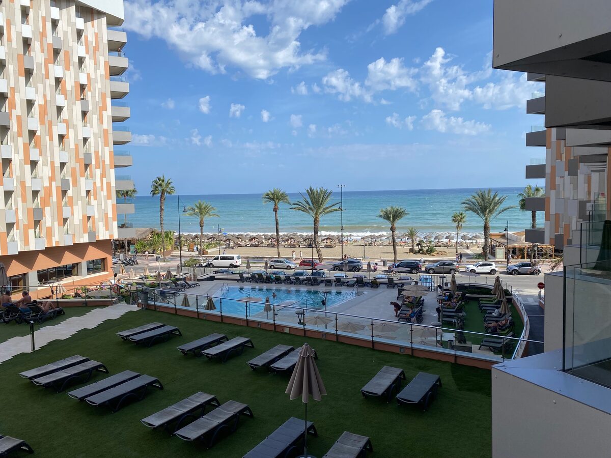 A pool, palm trees, and the sea, seen from a balcony of the conference hotel in Málaga.
